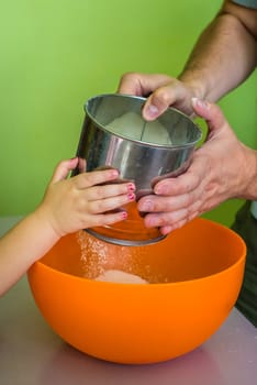 Children and dad hands Sift flour in yellow bowl