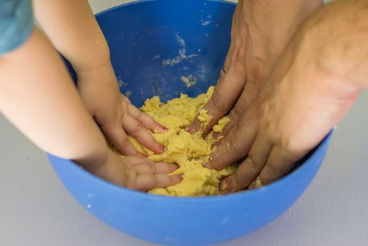 Children and dad hands preparing shortbread dough in blue bowl