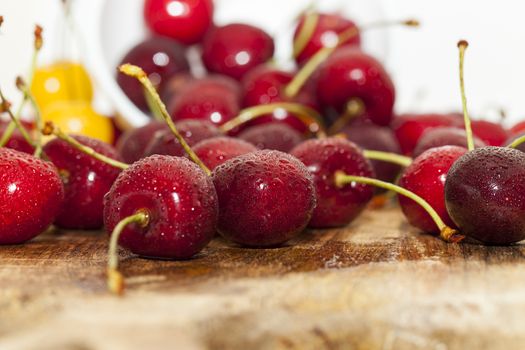 Photographed close-up ripe red cherries covered with drops of water, little depth of field, berries are on the wooden table