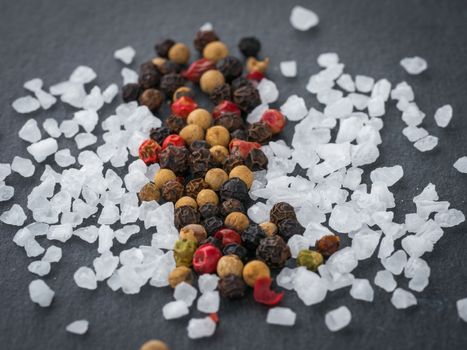 Coarse sea salt and peppercorns on slate background.Close up. Food background