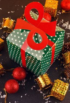 Big green gift box and christmas ornaments on wooden table