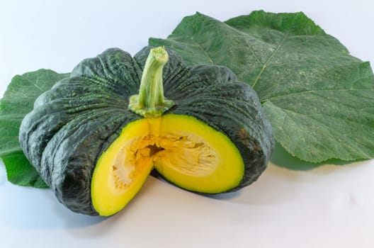 A yellow piece of pumpkin and green pumpkin  leaf on white background.