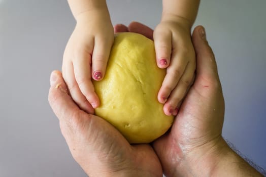 Children and dad hands hold the shortcrust dough over the table