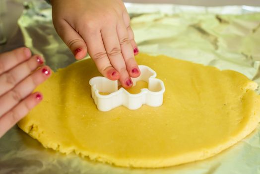 child makes shape of shortcrust dough with cookie cutters