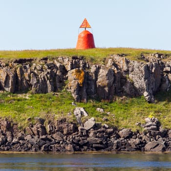 Cute little red lighthouse on a basalt island at the harbor of Stykkisholmur, Iceland