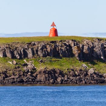 Cute little red lighthouse on a basalt island at the harbor of Stykkisholmur, Iceland