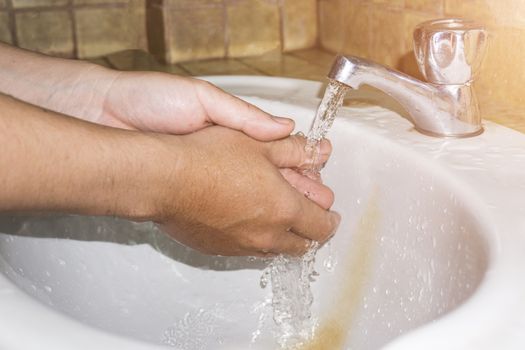 Boy washes hands with running water.