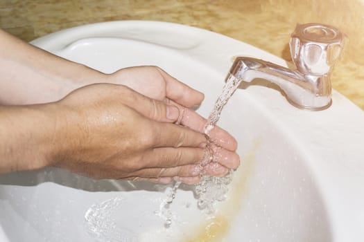 Boy washes hands with running water.