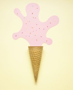 Creative concept photo of an empty waffle cone with a stain  made of paper on yellow background.