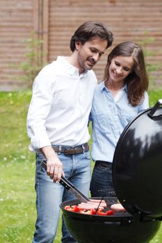 Happy couple cooking food on barbecue