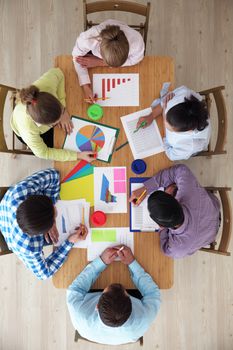 Diverse people aitting around the table with diagrams and financial reports