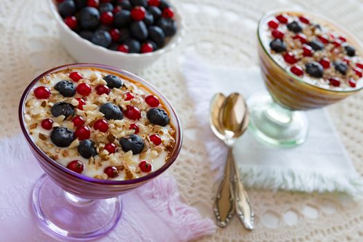 Closeup of two yogurt dessert with berries and almonds over a tablecloth