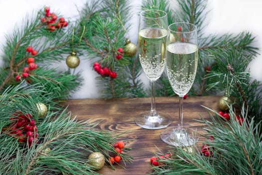Christmas and New Year seasonal composition with pine tree branches, two glasses of champaign, golden balls ornament and red rowan berries