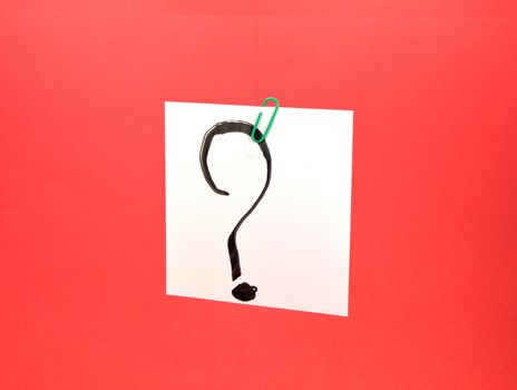 Question mark drawn on a post it in front of a red background