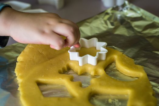 child makes shape of shortcrust dough with cookie cutters
