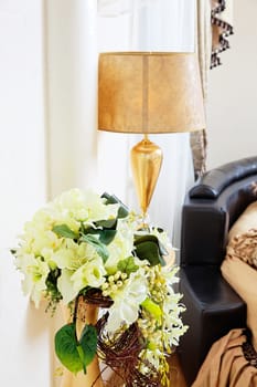 Golden vase with flowers near beautiful golden table lamp