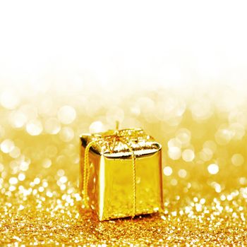 Decorative golden box with holiday gift on shiny glitter background