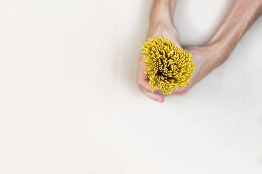 Top view bunch of  uncooked spaghetti in male hands on light craft paper