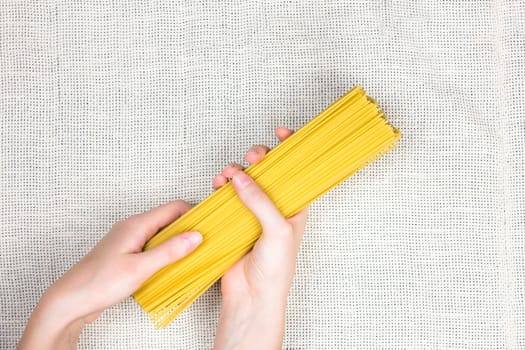 Top view of bunch uncooked spaghetti on light canvas background