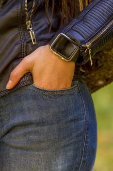 Young girl wears smart watch with hand in pocket. Focus on smart watch!