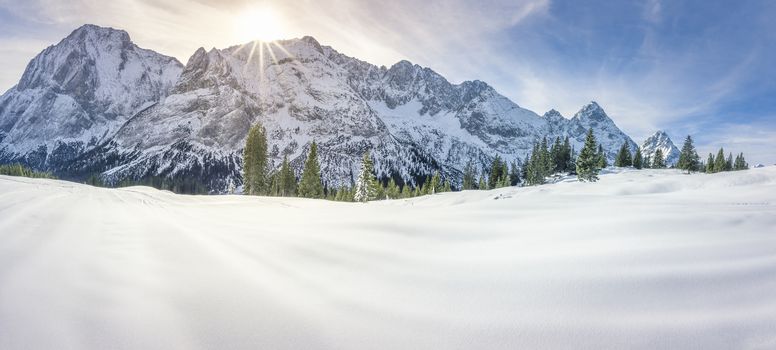 Dreamy winter panorama with the Austrian Alps mountains, the fir forests and a thick layer of snow over a valley, on a sunny day of December.