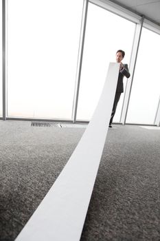 Office worker unrolling long sheet of paper