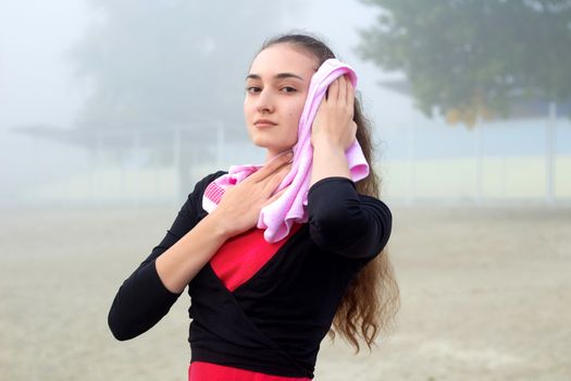 Young pretty slim fitness sporty woman with towel during break at training workout outdoor