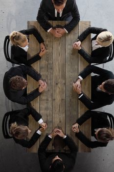 Group of business people team sitting around empty wooden table at meeting