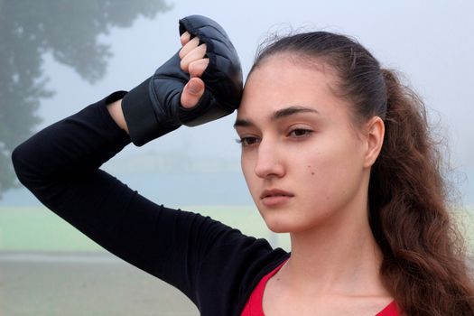 Young pretty slim fitness sporty woman rests during boxing training workout outdoor