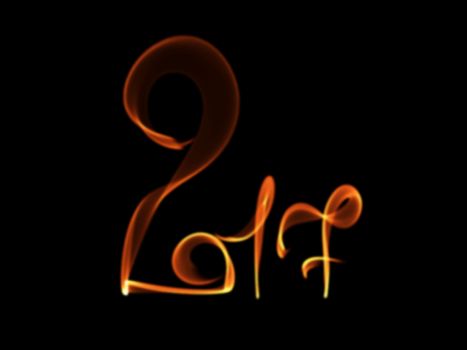 Happy new year 2017 isolated numbers lettering written with fire flame or smoke on black background.