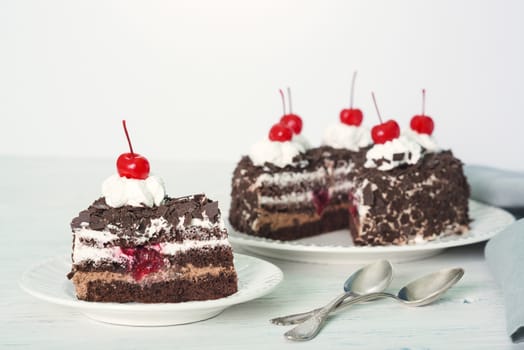 Chocolate cake with cherry on plate on light background