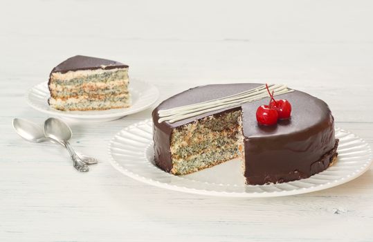 Chocolate-covered poppy seed cake with cherries on plate 