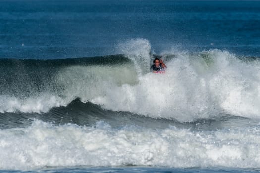 Bodyboarder in action on the ocean waves on a sunny day.