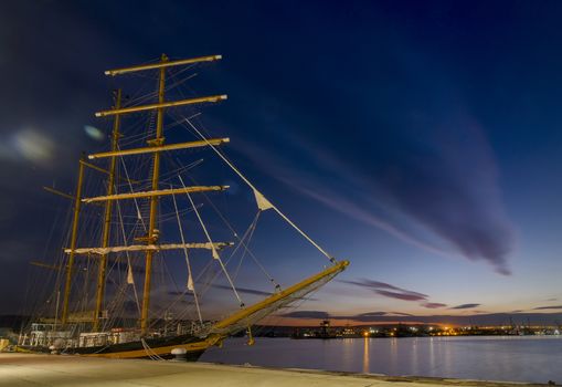 sailboat in port at sunset. Clouds reflection