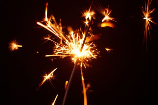 Sparkler on a black background, sparks fly in different directions, Christmas atmosphere