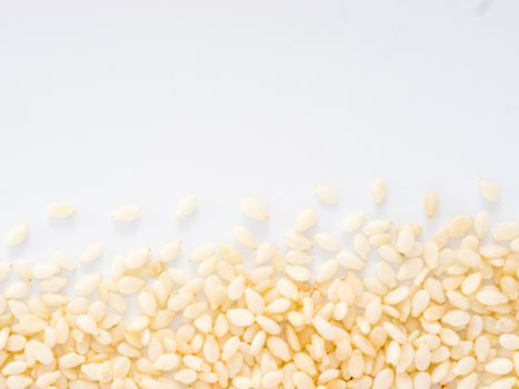 Sesame Seeds on white background with copy space. Isolated one edge. Top view or flat lay.