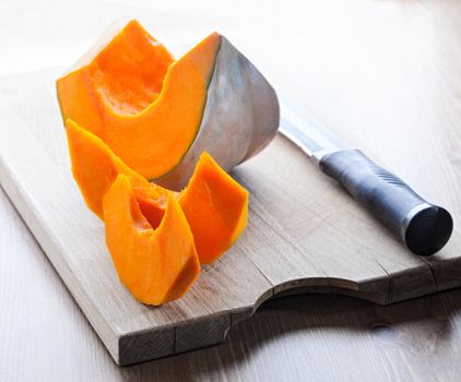 Sliced Pumpkin and knife on a wooden board.