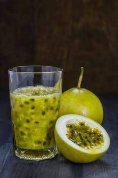 Fresh passion fruit juice in glass with passion fruits over wooden background , still life