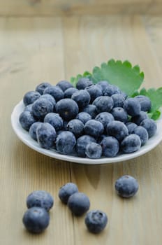 Blueberries on white plate over  wooden background
