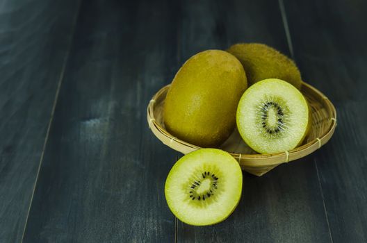 kiwi fruit and sliced with bamboo basket on wooden background , still life