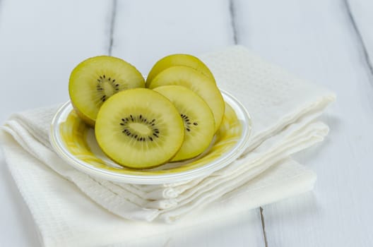 golden kiwi fruit and sliced on dish over white wooden background