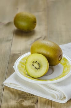 golden kiwi fruit and sliced on dish over wooden background