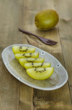 golden kiwi fruit and sliced on dish over wooden background