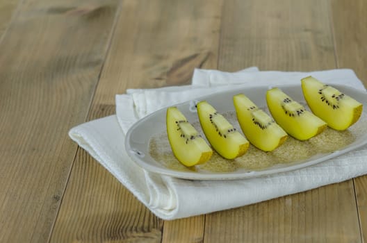 sliced of golden kiwi fruit  on dish over wooden background