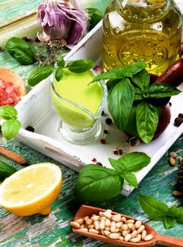 Freshly Made Creamy Pesto Sauce with Raw Fresh Ingredients, Olive Oil and Pine Nut in White Wooden Tray closeup Cracked Wooden background