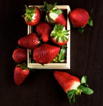 Big Fresh Ripe Strawberries in Wooden Box closeup on Dark Wooden background. Top View
