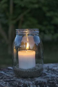 View of glass jar with lit candle inside