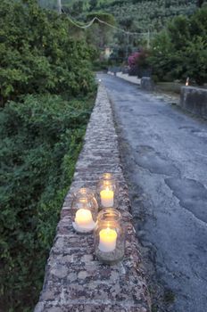 Glass jars with lit candles on stone wall
