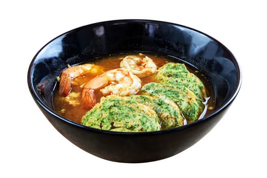 Hot and sour soup curry with shrimps and acacia pennata omelette. In black dish on white background. Objects with clipping paths.