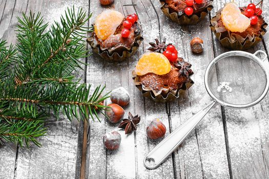 little cupcakes in tins ,decorated with berries and a slice of tangerine